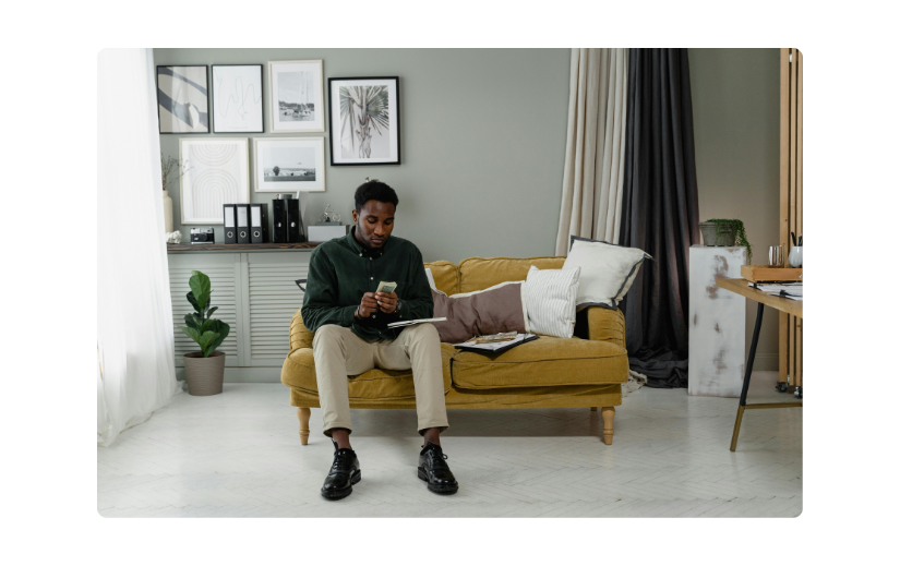 Man sitting on a cozy sofa working on his phone, ideal for exploring side hustles from home in a productive environment.